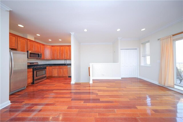 kitchen featuring sink, light hardwood / wood-style flooring, stainless steel appliances, and ornamental molding