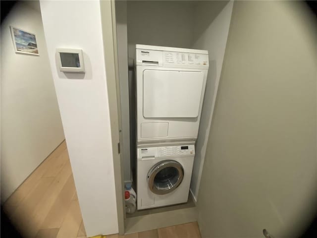 washroom with light hardwood / wood-style flooring and stacked washer and clothes dryer