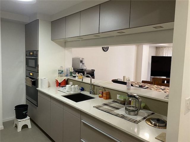 kitchen with light tile patterned flooring, double oven, gray cabinetry, and sink