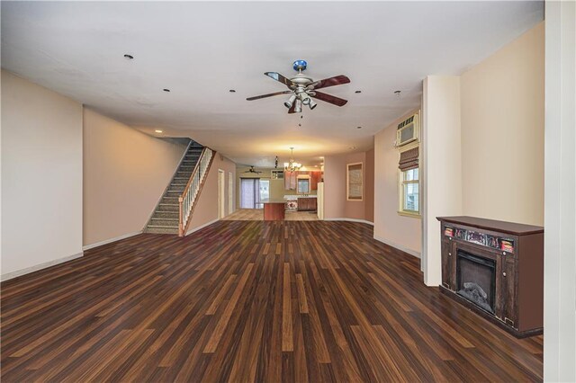 unfurnished living room with ceiling fan with notable chandelier and dark hardwood / wood-style flooring