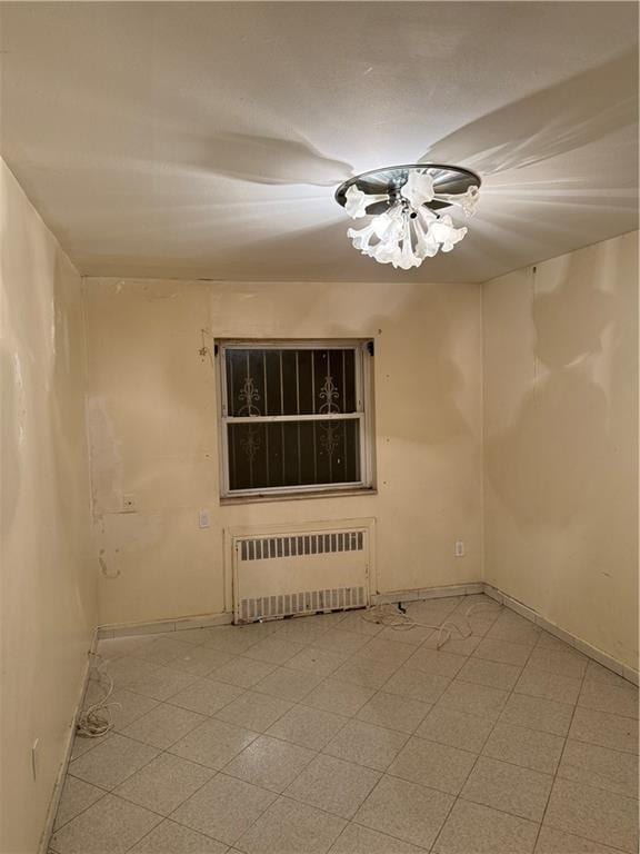 2069 E 55th St, Brooklyn, NY 11234 - unfurnished room featuring baseboards, radiator heating unit, and a chandelier