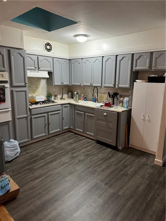 kitchen with sink, decorative backsplash, stainless steel gas cooktop, white oven, and dark wood-type flooring