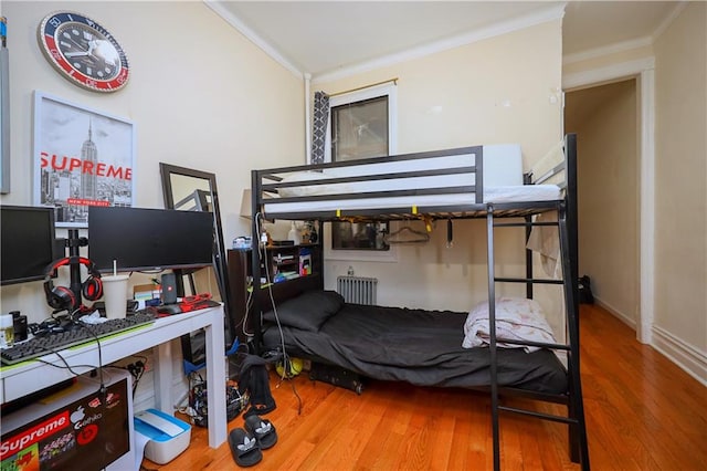 bedroom featuring wood-type flooring, ornamental molding, and radiator