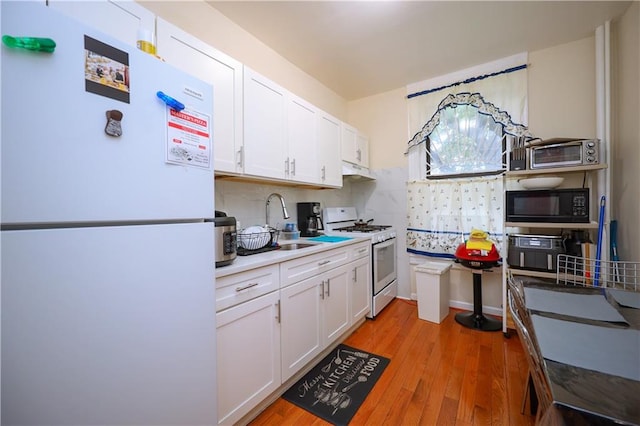 kitchen featuring white cabinetry, white appliances, sink, and light hardwood / wood-style flooring