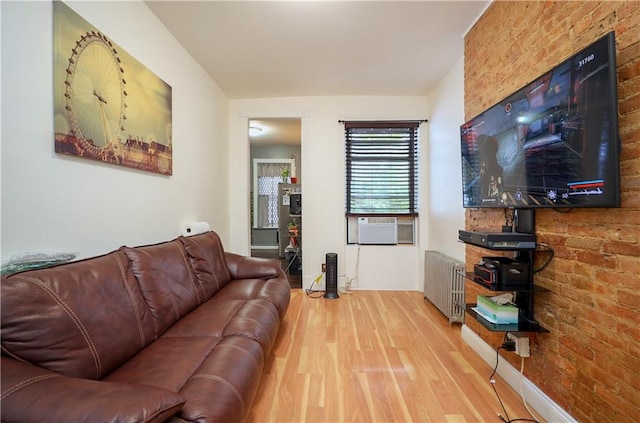 living room featuring wood-type flooring, radiator, cooling unit, and brick wall