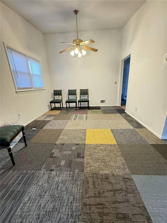 interior space with ceiling fan, a towering ceiling, and dark carpet