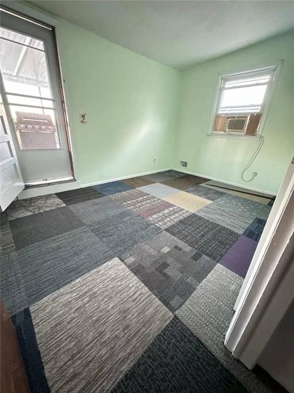 carpeted empty room featuring cooling unit and baseboards