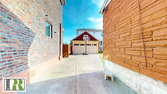 view of side of home with an outdoor structure, fence, and a detached garage