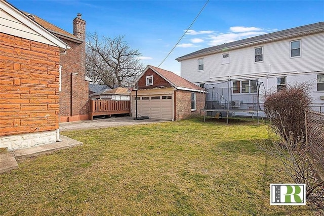 view of yard featuring fence, an outbuilding, a trampoline, and a garage