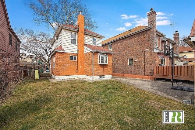 rear view of property with a chimney, a wooden deck, fence, a yard, and a patio