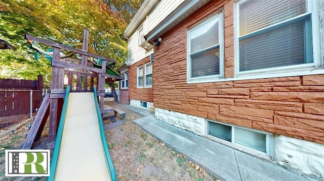 view of side of home featuring stone siding and fence