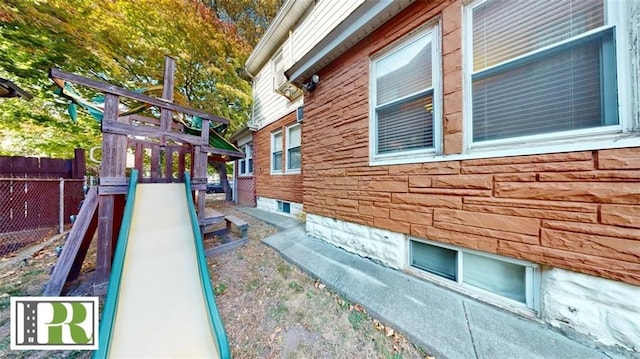 view of home's exterior featuring a playground and fence