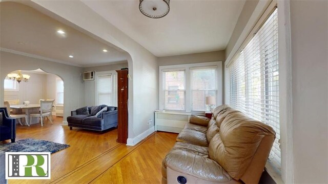 living room featuring an AC wall unit, wood-type flooring, and an inviting chandelier