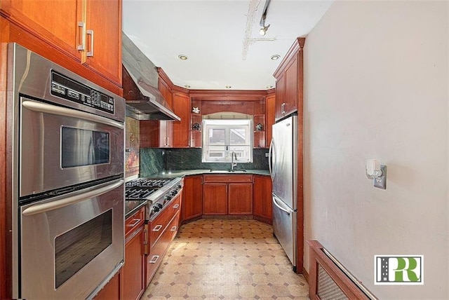 kitchen featuring stainless steel appliances, a sink, light floors, tasteful backsplash, and brown cabinetry