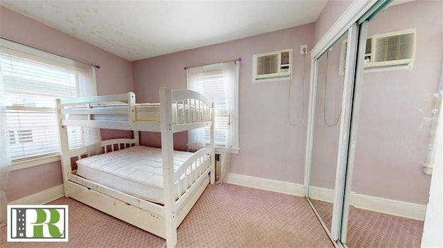 carpeted bedroom with a closet, an AC wall unit, and baseboards