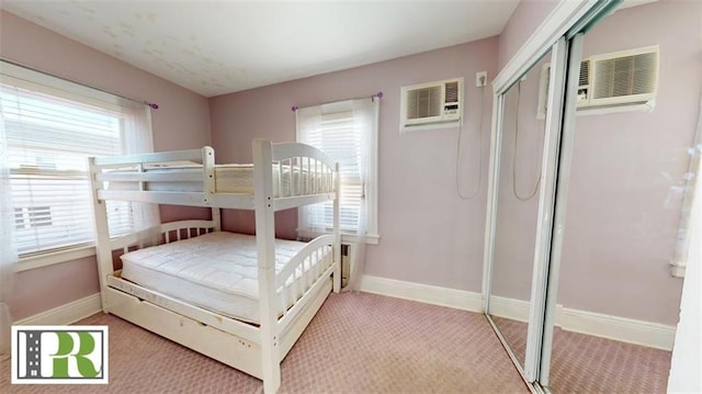 bedroom with carpet flooring, baseboards, a wall mounted AC, and a closet
