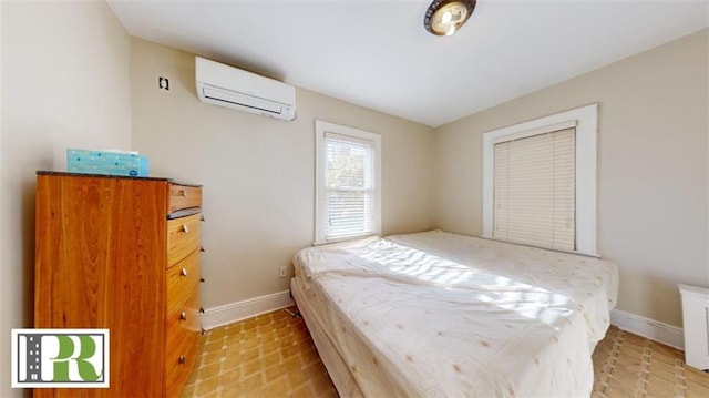 bedroom with an AC wall unit and baseboards