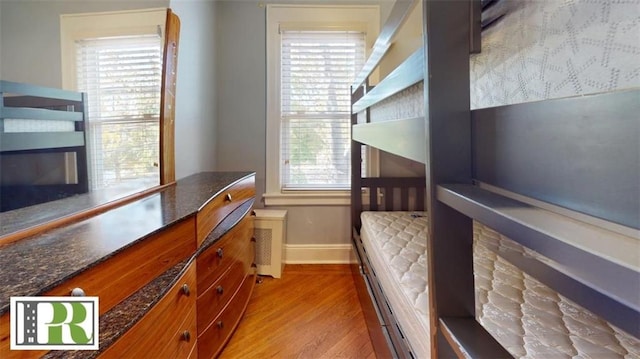 bedroom featuring baseboards, a glass covered fireplace, and light wood-style floors