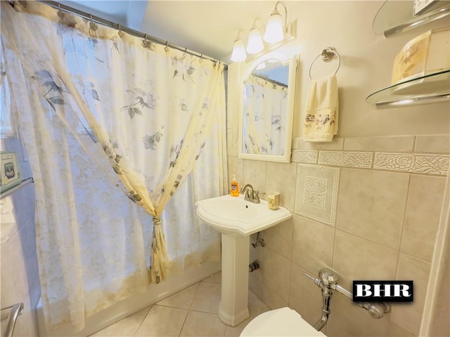 full bath with shower / tub combo with curtain, tile walls, toilet, and tile patterned floors