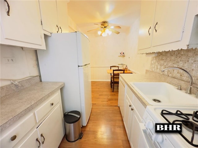 kitchen featuring white cabinetry, sink, white appliances, and light wood-type flooring