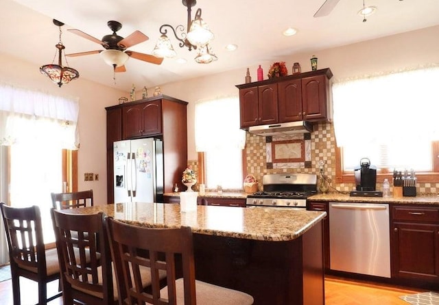 kitchen with a healthy amount of sunlight, a kitchen island, and appliances with stainless steel finishes