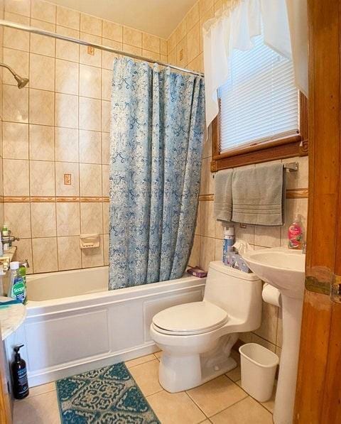 full bathroom featuring toilet, shower / tub combo with curtain, tile walls, and tile patterned floors