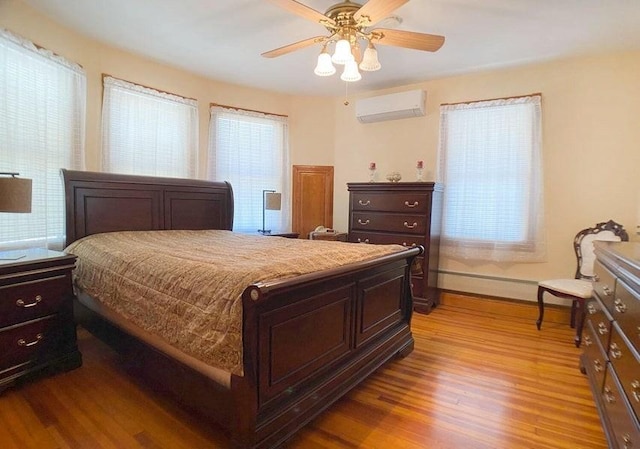 bedroom with a wall unit AC, multiple windows, ceiling fan, and light hardwood / wood-style flooring