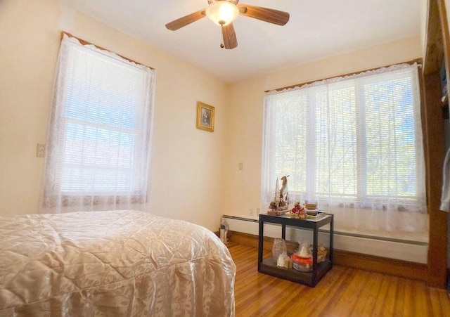 bedroom featuring multiple windows, hardwood / wood-style flooring, and ceiling fan