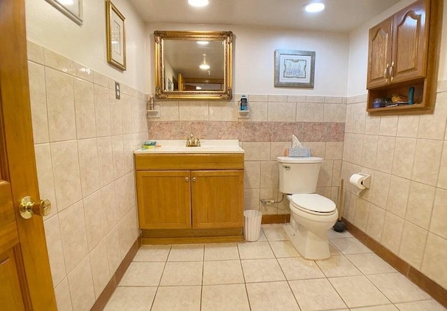 bathroom with vanity, toilet, and tile walls