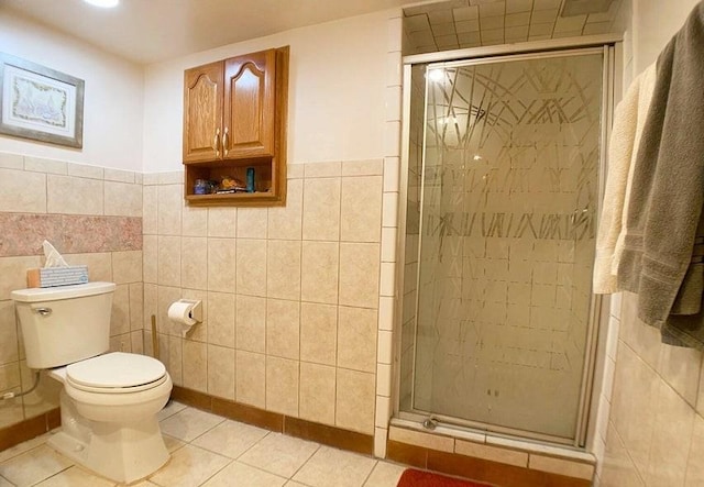 bathroom featuring tile walls, tile patterned floors, toilet, and a shower with shower door