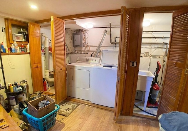 clothes washing area featuring electric panel, light hardwood / wood-style flooring, and independent washer and dryer