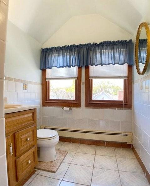 bathroom with tile walls, tile patterned flooring, a healthy amount of sunlight, and a baseboard heating unit