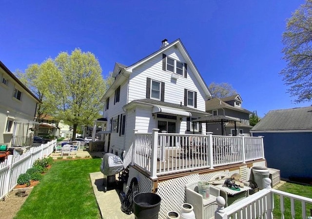 rear view of house featuring a lawn and a wooden deck