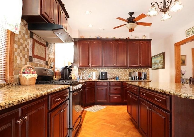 kitchen with tasteful backsplash, light parquet floors, light stone counters, exhaust hood, and stainless steel range with gas cooktop