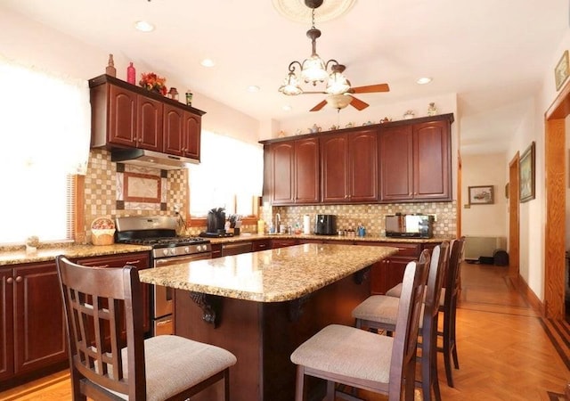 kitchen with a kitchen breakfast bar, stainless steel range with gas stovetop, and tasteful backsplash