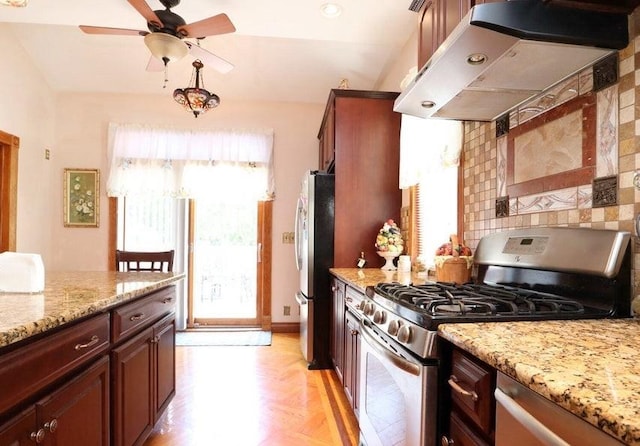 kitchen featuring ventilation hood, appliances with stainless steel finishes, ceiling fan, and light stone countertops