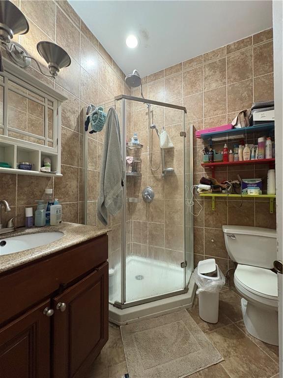 bathroom with vanity, a shower with door, tile patterned floors, and tile walls