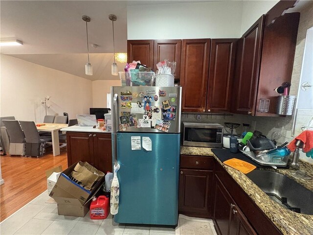 kitchen featuring decorative backsplash, stainless steel appliances, sink, light hardwood / wood-style flooring, and hanging light fixtures