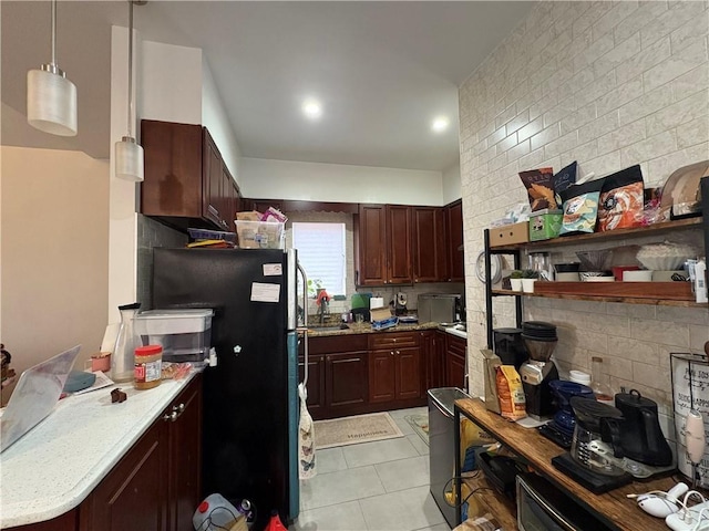 kitchen featuring pendant lighting, decorative backsplash, light tile patterned flooring, and black refrigerator