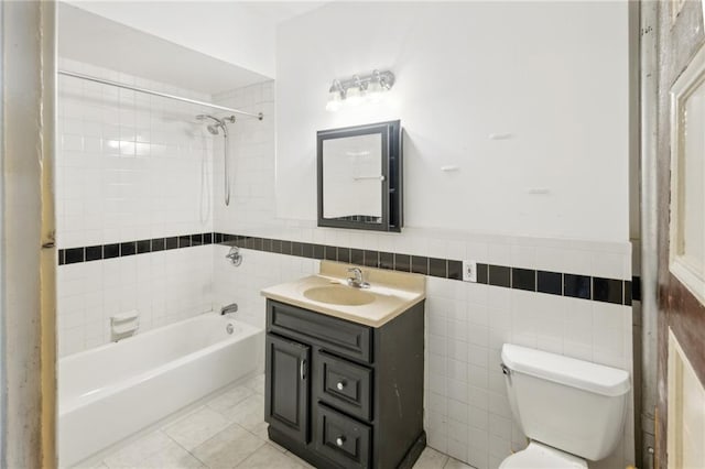 full bathroom with toilet, tile walls, tile patterned floors, tiled shower / bath, and vanity