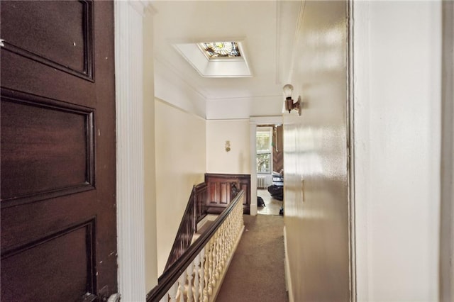 corridor with a skylight and dark colored carpet