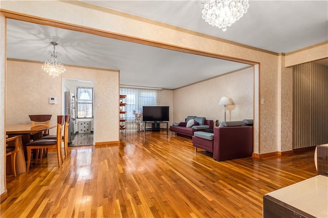 living room with wood-type flooring, ornamental molding, and a chandelier