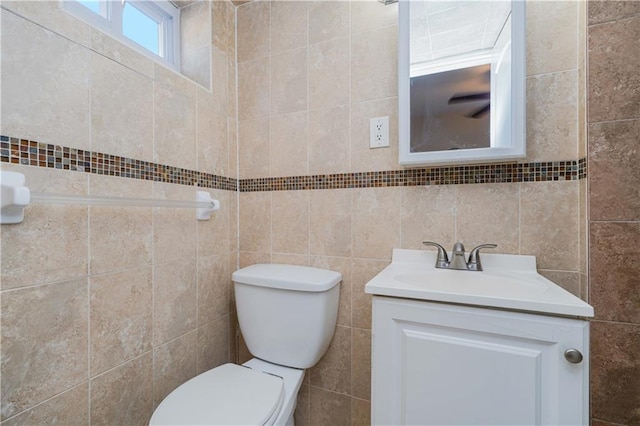 bathroom featuring vanity, toilet, and tile walls