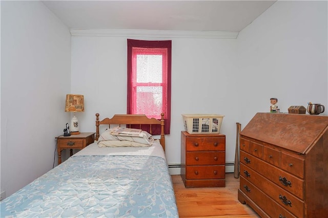 bedroom featuring light wood-type flooring, crown molding, and a baseboard heating unit