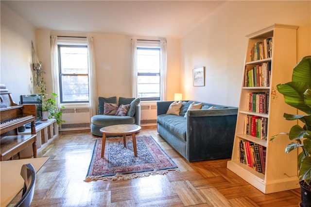 sitting room featuring plenty of natural light, radiator heating unit, and parquet flooring