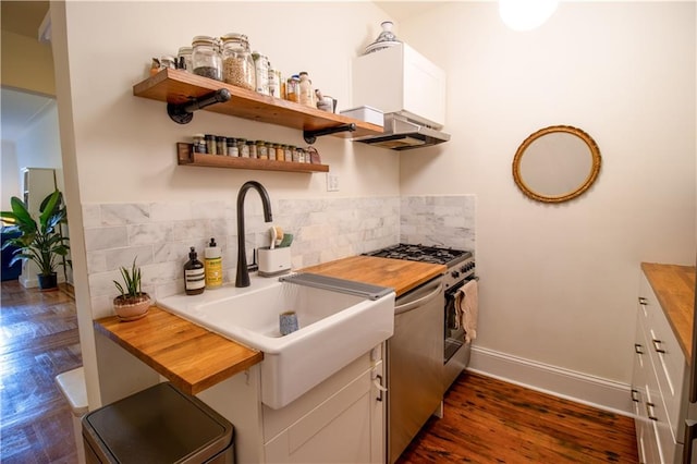 kitchen with tasteful backsplash, butcher block counters, sink, and white cabinets