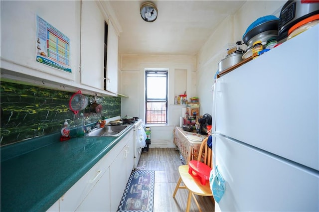 kitchen featuring white cabinets, sink, tasteful backsplash, and white fridge