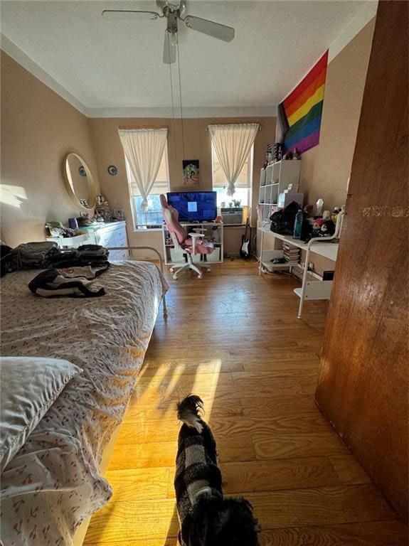 bedroom featuring wood-type flooring, ceiling fan, and ornamental molding