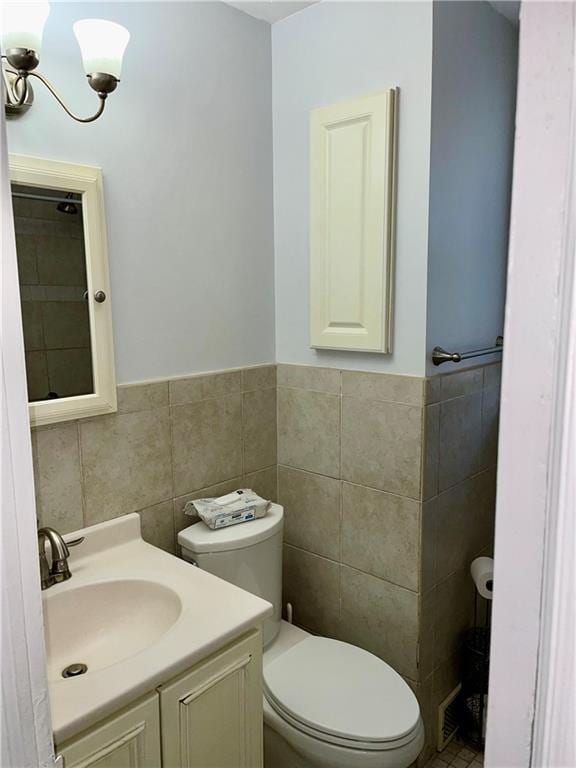 bathroom featuring tile walls, a chandelier, vanity, and toilet