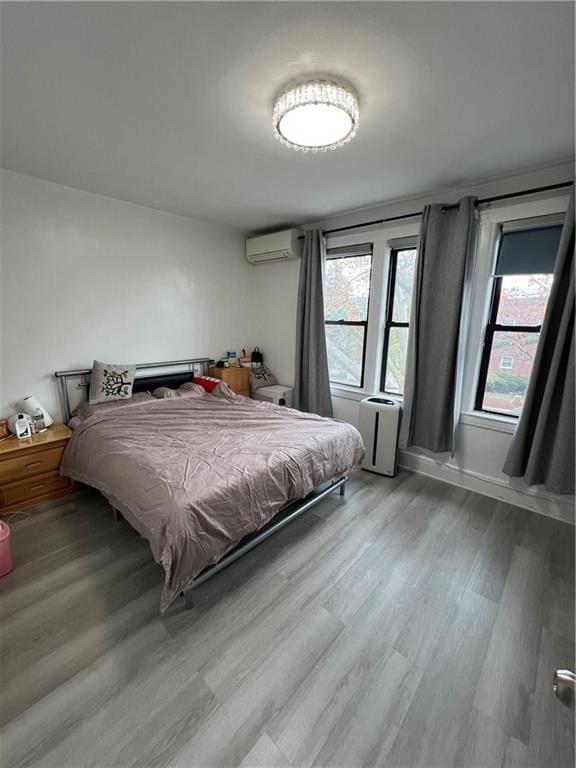 bedroom with a wall mounted air conditioner and light hardwood / wood-style floors